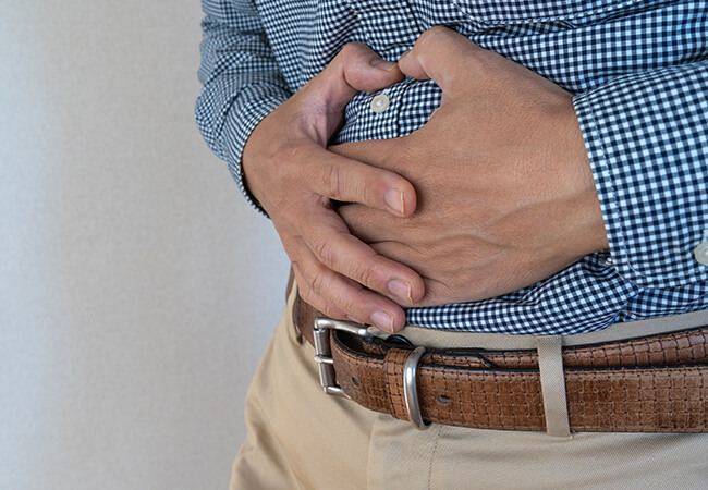 腹痛でお腹をおさえる男性